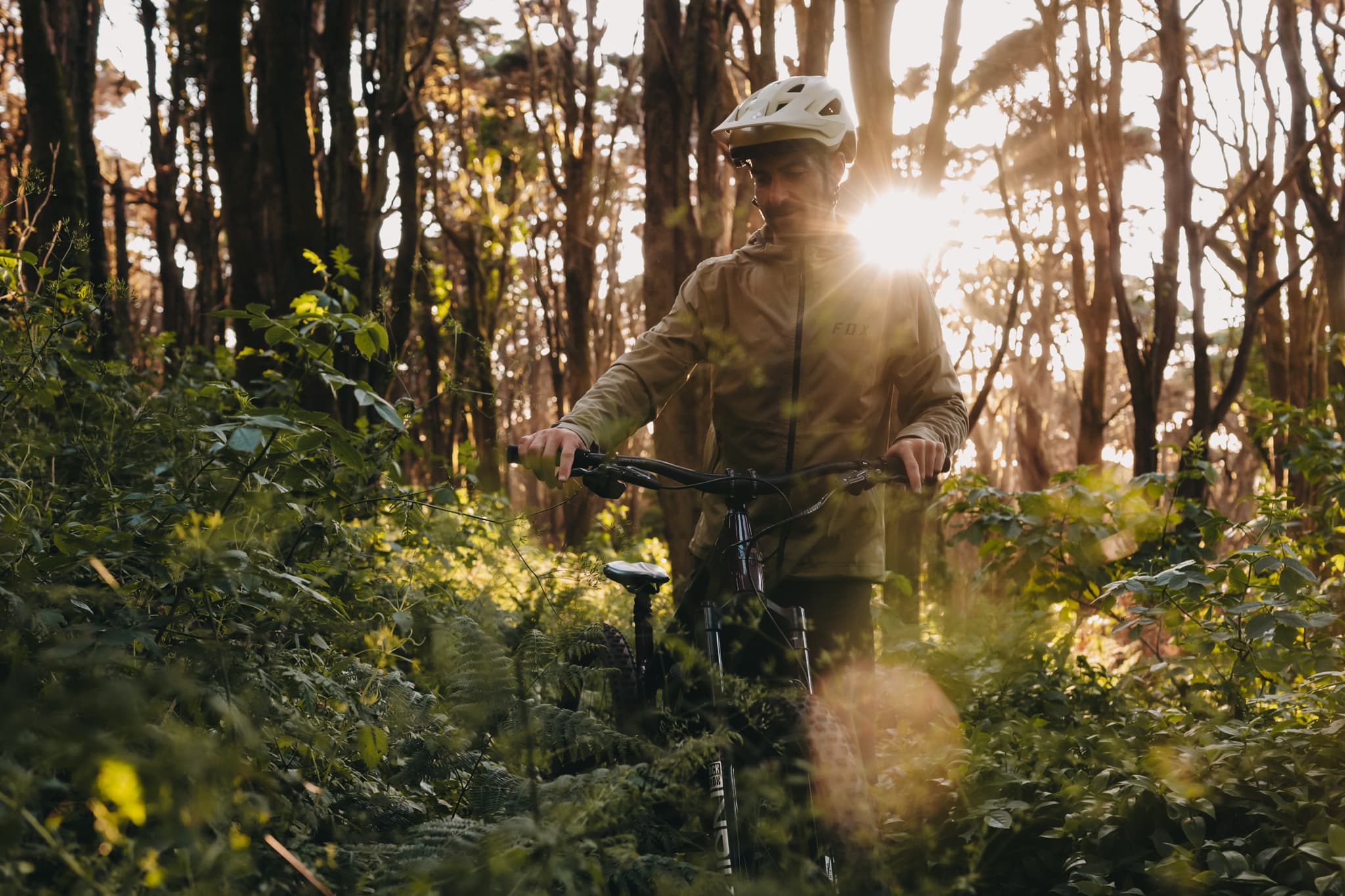 Marcel wheeling his mountain bike through a sunlit Sintra forest