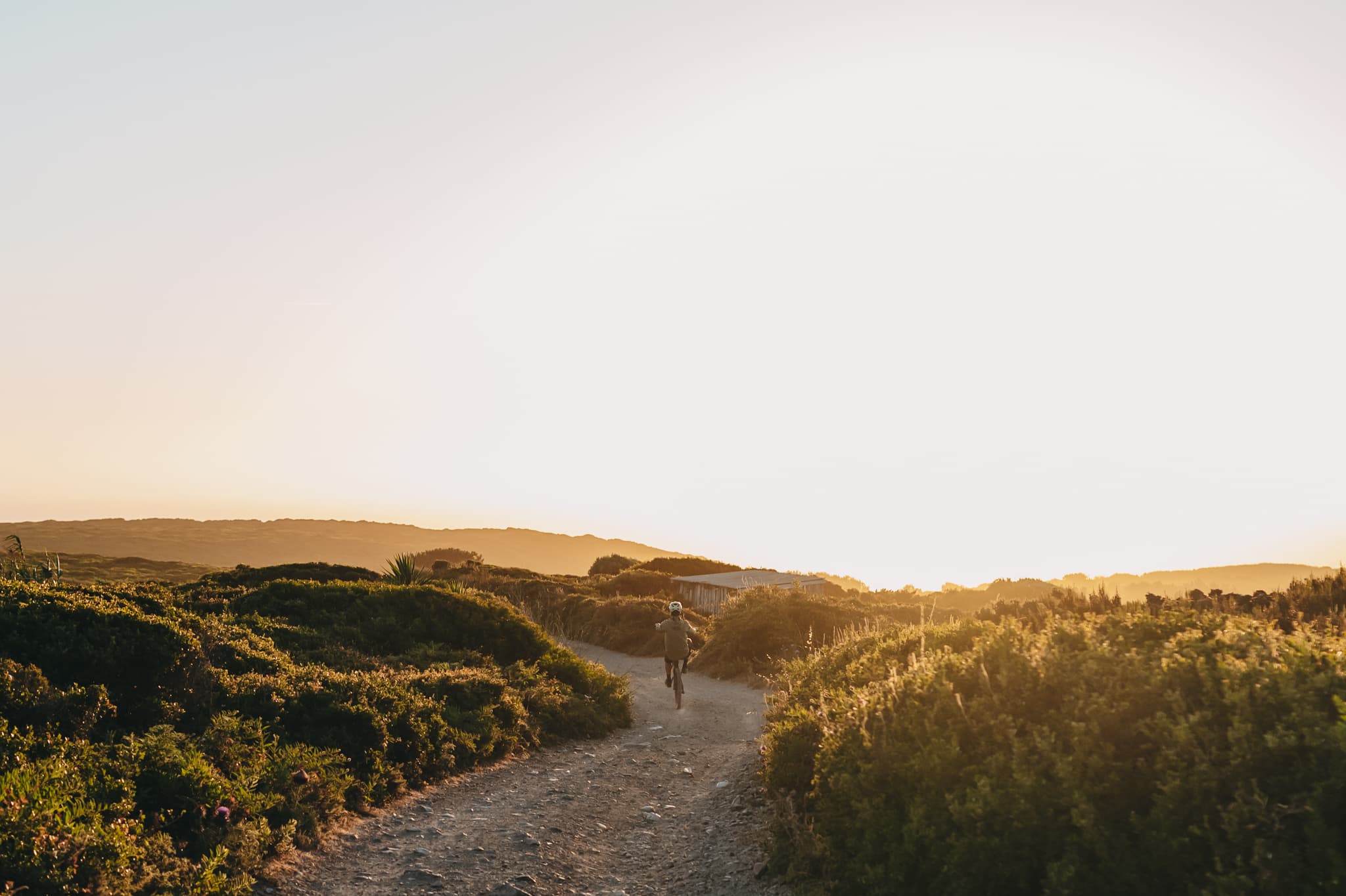 A rider heading down a sandy coastal trail near Sintra at golden hour